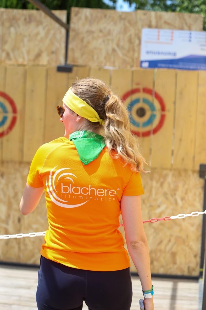 Collaborateurs de Blachere Illumination en pleine épreuve de lancer de hache pendant le Challenge Inter-Entreprises, sous une forte chaleur estivale